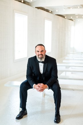 man in tuxedo sitting on bench and leaning on knees