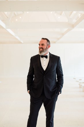 man in tuxedo standing with hands in pockets