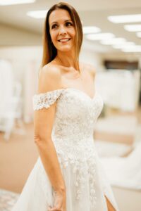 Aurora Bridal Boutique Bride wearing her wedding dress and smiling at herself.