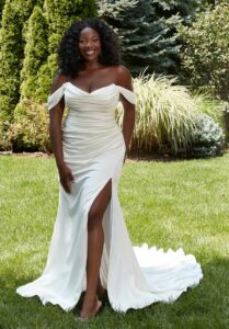 Stunning bride, striking a pose and smiling while wearing wedding dress from Aurora Bridal Boutique.