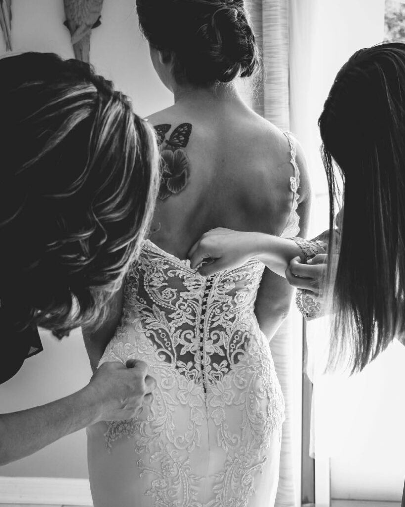 bridal stylist inspecting bridal gown on bride