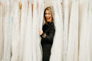 Aurora Bridal Boutique bridal stylist hiding in a rack of wedding dresses.