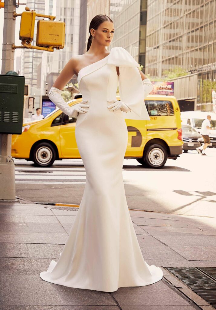 A bride wearing a dress fitted to her body with a large bow detail on her shoulder