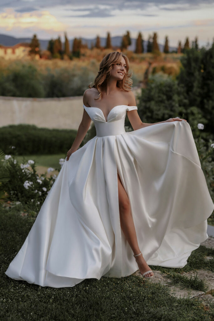 A bride with a big smile on her face walking through a natural setting in a white dress