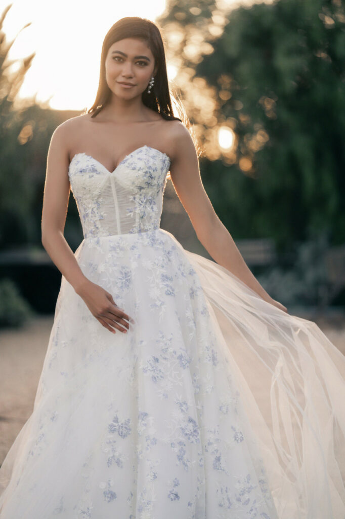 A wedding dress with blue floral decorations and a lacy train