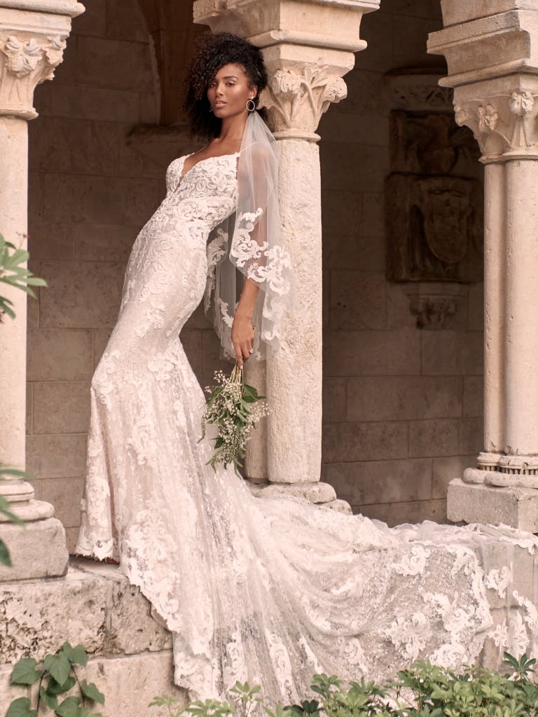 A bride in a decorative veil and a long wedding dress with lace detailing