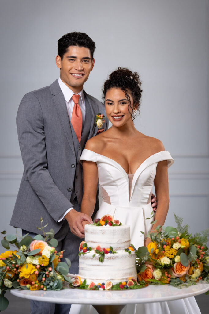 A newly married husband and wife cutting the cake at their wedding celebration.