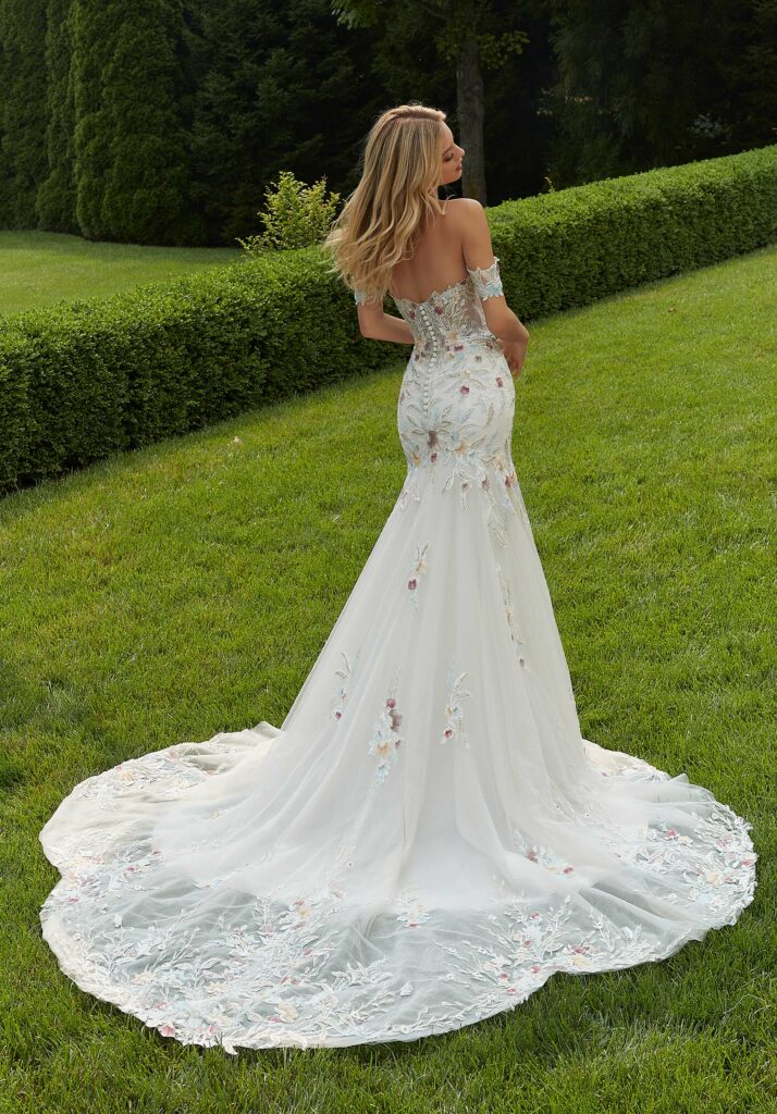 Bride wearing a floral bridal gown, standing in a lush garden surrounded by blooming flowers in Palm Bay.