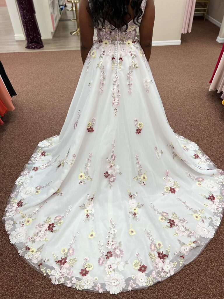 Close-up of a bride's floral dress train, showcasing intricate flower embroidery and beading.