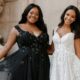 Two brides, one in a black floral gown and one in white, posing elegantly in a historic setting.