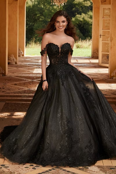 Bride in a stunning black lace wedding gown standing in an ornate archway.