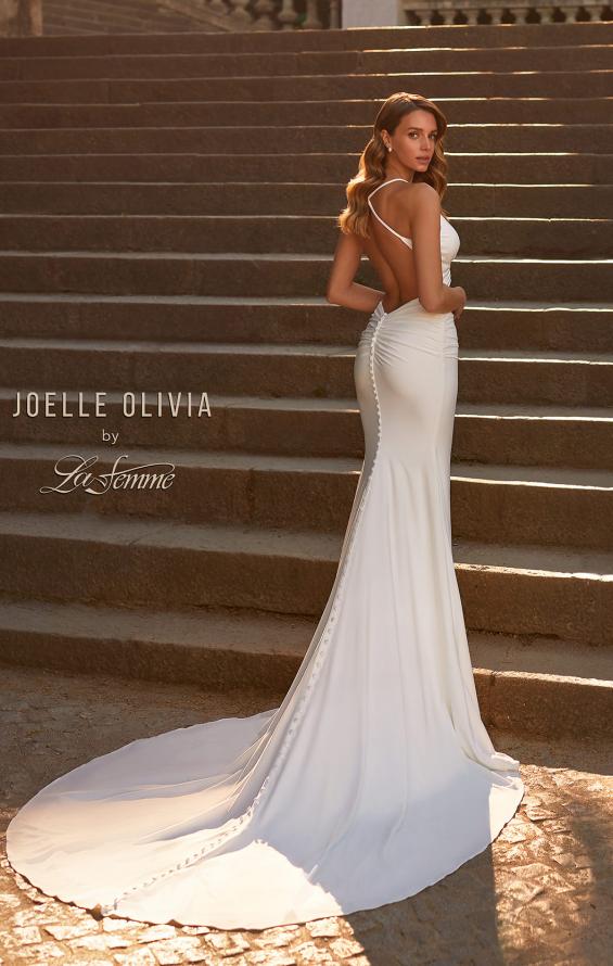 Graceful bride in white gown with strap details and a flowing train, posing on grand staircase.