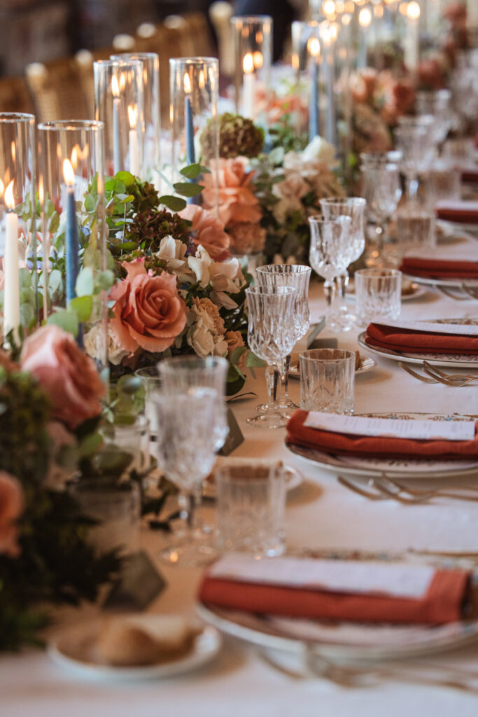 An elegant table with crystal glassware, soft floral arrangements, and flickering candles at a wedding reception.