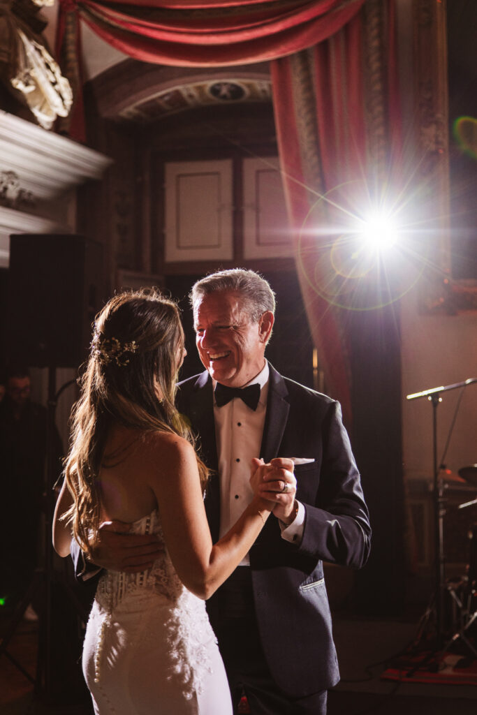 Bride sharing a heartfelt dance with her father in a beautifully decorated Italian wedding venue.