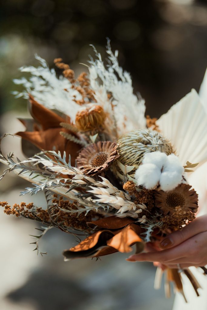 A boho-style dried flower bridal bouquet featuring warm earth tones, cotton stems, and dried foliage for a unique and textured wedding arrangement.