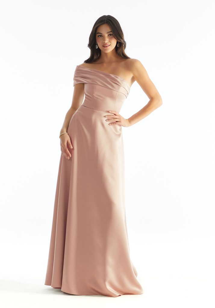 A bridesmaid glows in a blush pink satin gown with an off-the-shoulder neckline, fitted bodice, and a flowing skirt, ideal for spring bridesmaid dress colors.