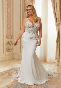 Bride wearing a fitted mermaid wedding gown with lace bodice and flowing train inside an elegant room.