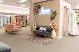 Fitting and waiting room inside Aurora's Bridal Boutique with pink and blue couches and floral accents throughout the room.