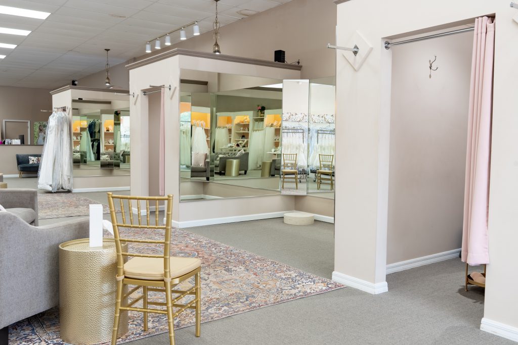 An empty bridal fitting area with mirrors, seating, and soft neutral d&eacute;cor arranged throughout the boutique.