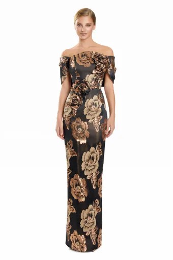 A woman models a black off-the-shoulder evening gown with large gold floral patterns against a plain light gray background.